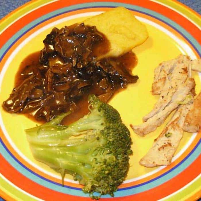 Slow Cooker Polenta with Mushroom Sauce, shown with broccoli and sautéed vegetarian chicken strips.