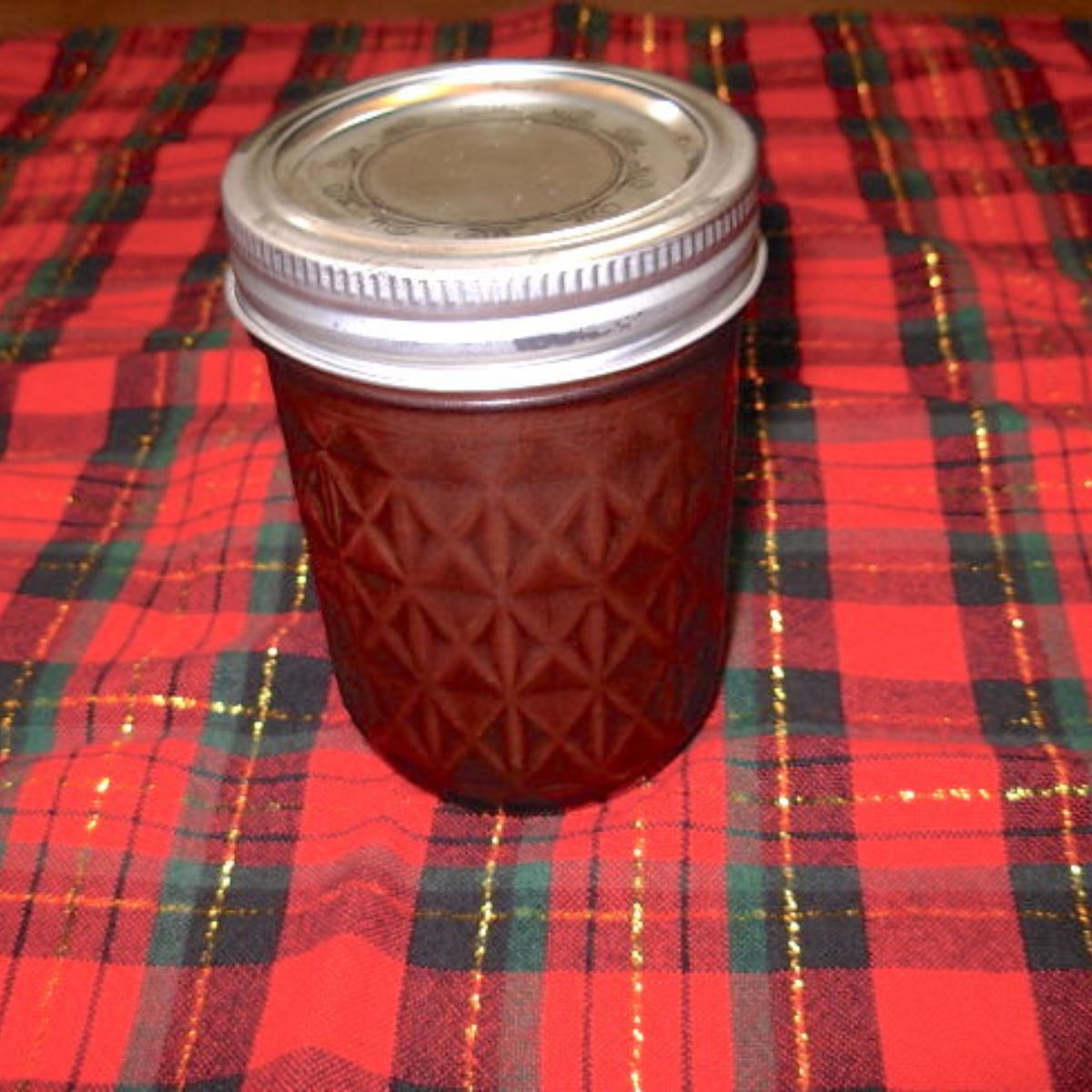 A jar of chocolate sauce sitting on pretty Christmas fabric