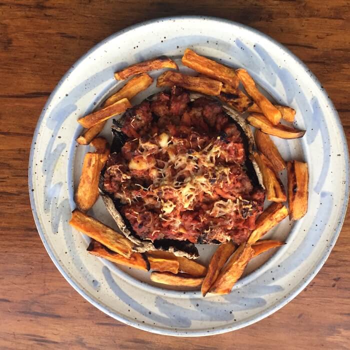 Pizza burger made with on a portobello mushroom cap and served with roasted sweet potato "fries."