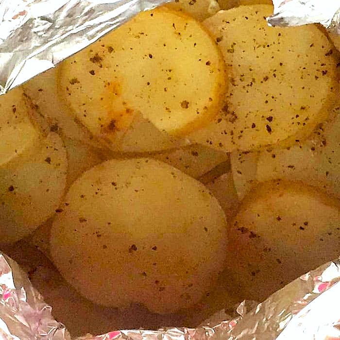 sliced grilled potatoes and ontions in foil packet for cooking