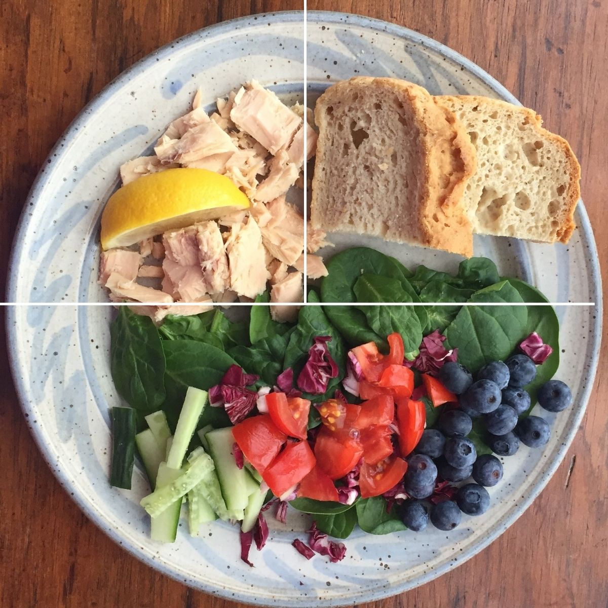 a plate with salad, chicken and bread