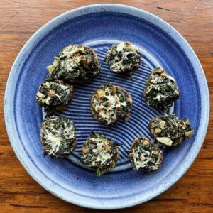 Spinach Stuffed Mushrooms shown on a plate by Elizabeth Krome.