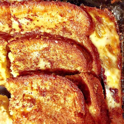 Slices of golden-brown overnight baked French toast with a custard base, topped with cinnamon and visible baked raisins, served in a baking dish.