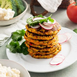 a stack of cauliflower and broccoli fritters on a white plate