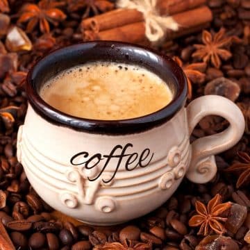 a coffee mug placed on top of coffee beans and spices