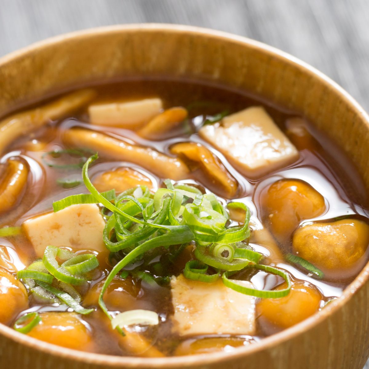 a bowl of soup with tofu pieces simmered in it