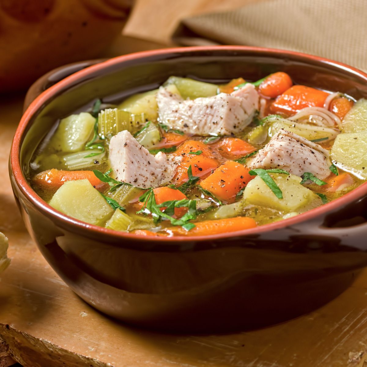 hearty turkey soup in a brown bowl