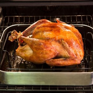 A roasted turkey in a light green pan.