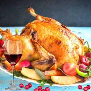 A roasted turkey with vegetables and a glass of wine.