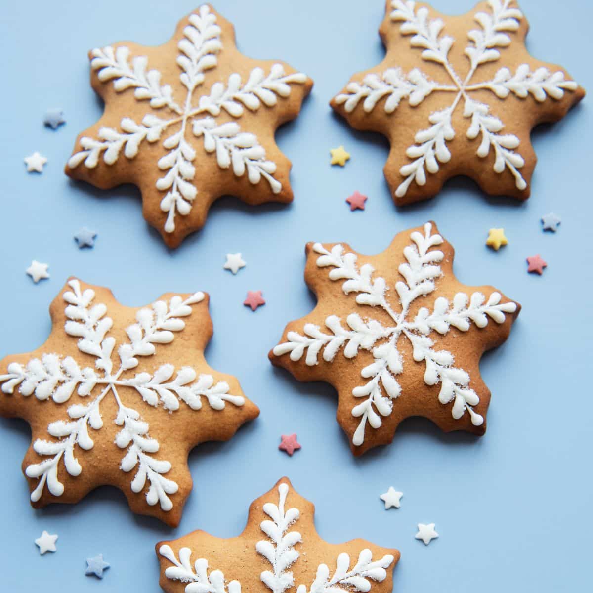 Star shaped cookies decorated with white frosting, to look like snowflakes. 