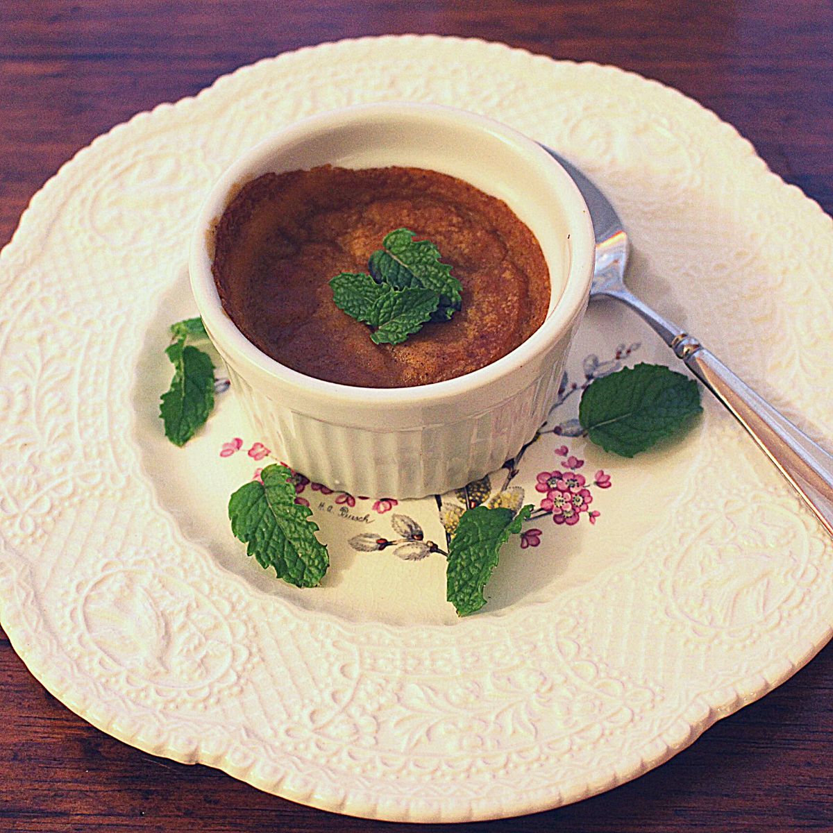 Vegan pumpkin pudding on a pretty while plate and garnished with fresh mint leaves.