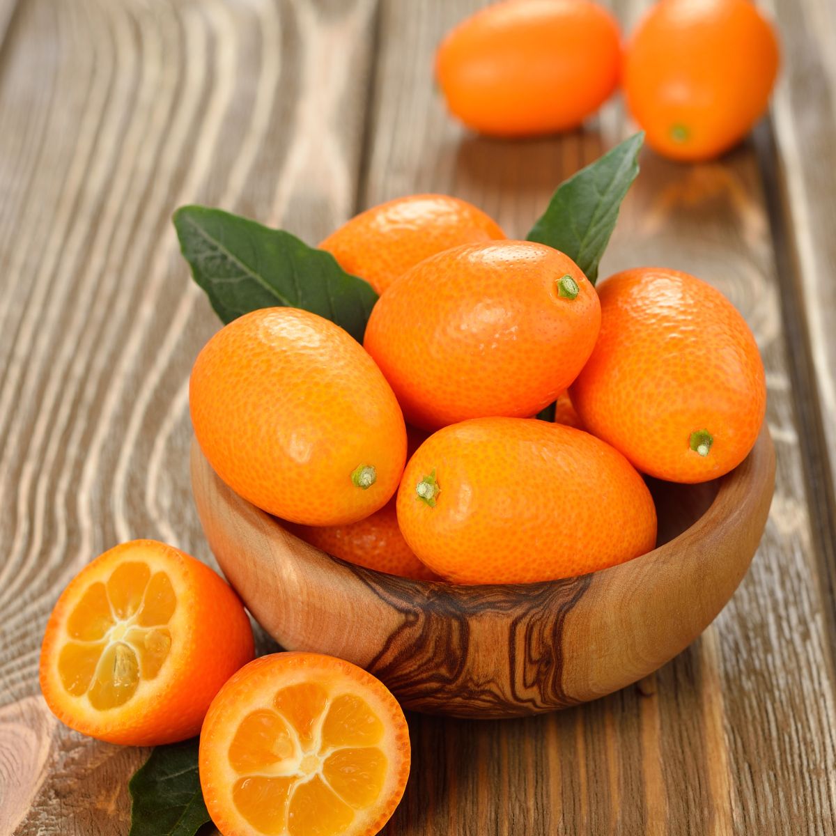 a bowl of kumquat fruits on a wooden table. 