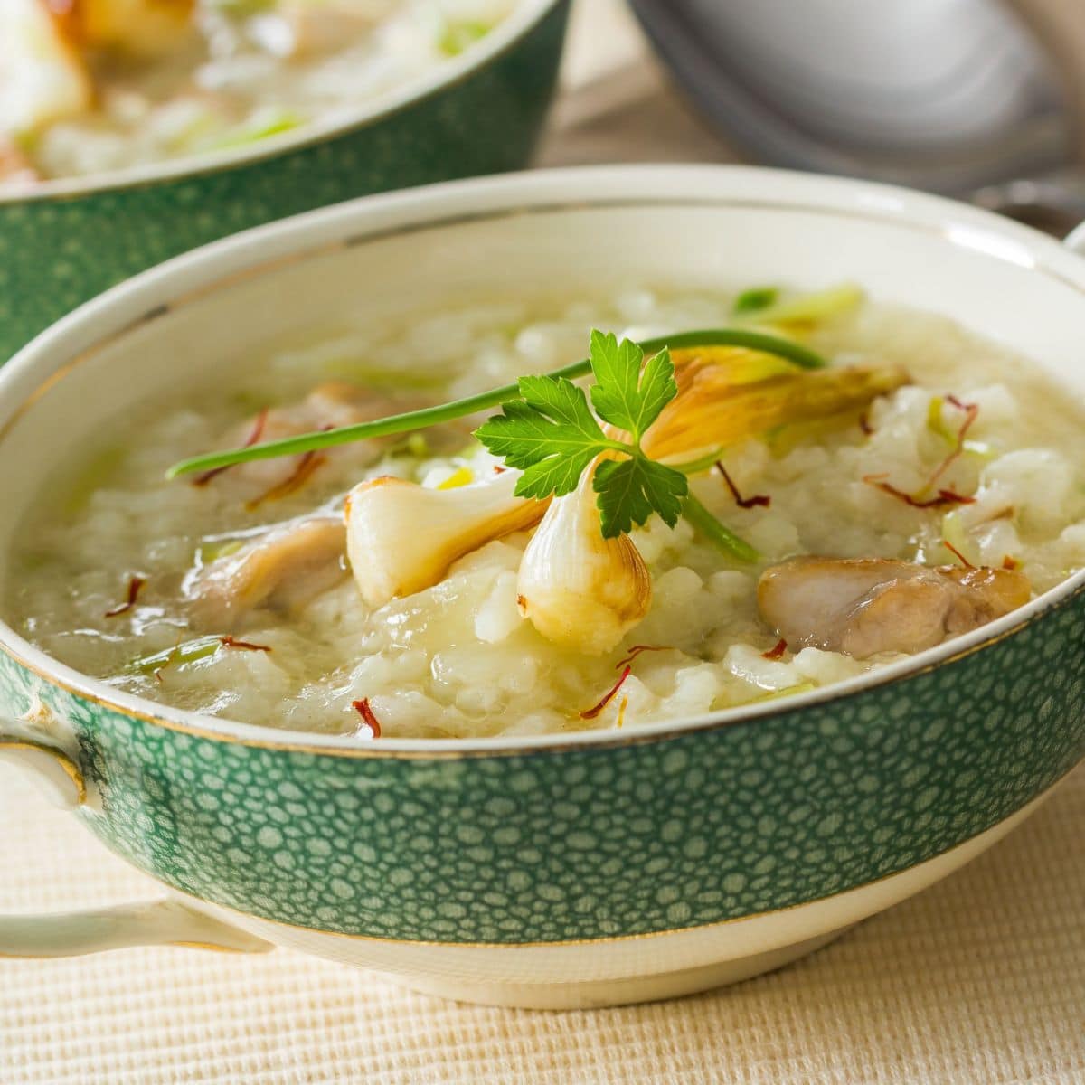 Chicken and rise soup in a pretty bowl with a green stripe.