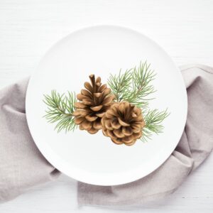 White plate with pinecone design, on a gray kitchen towel.