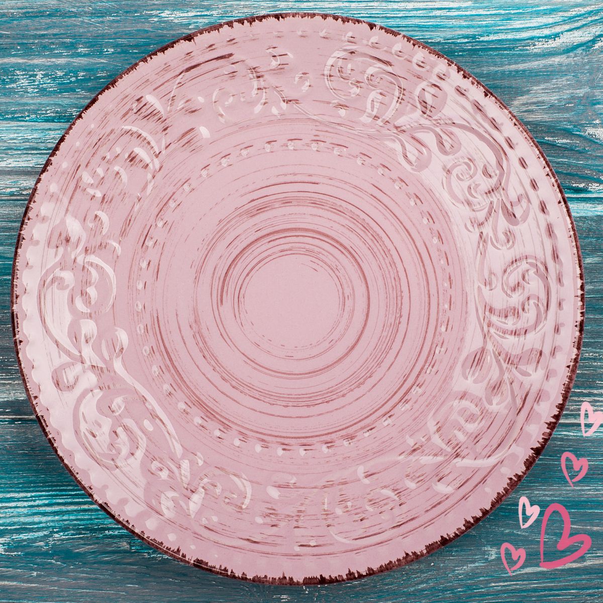 Beautiful pink plate on a teal painted wooden surface. 