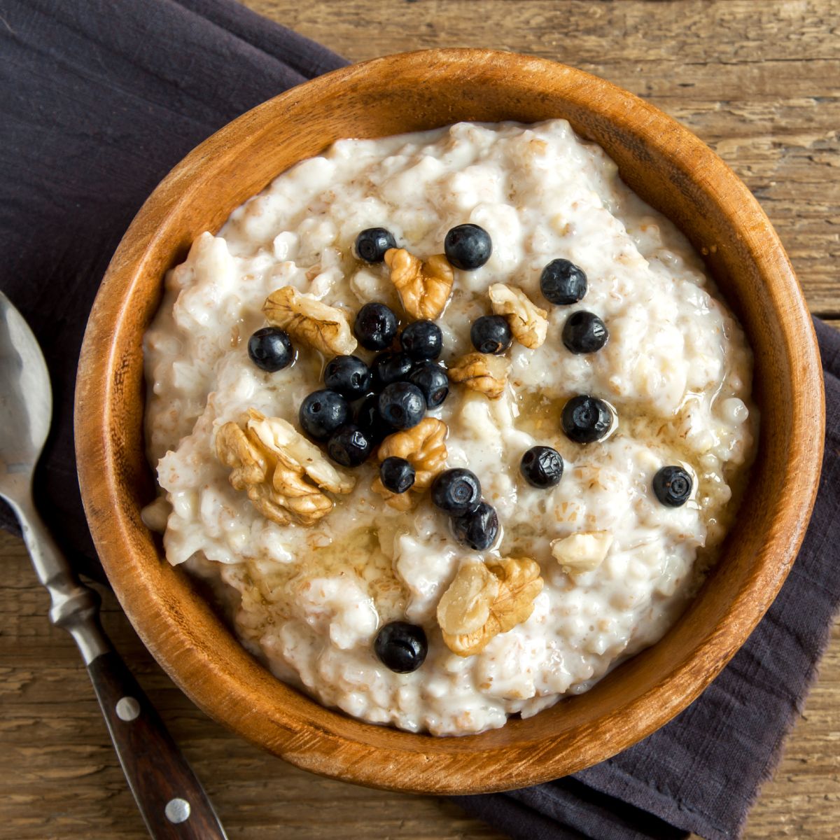 a wooden bowl with oatmeal, fruit, and nuts.