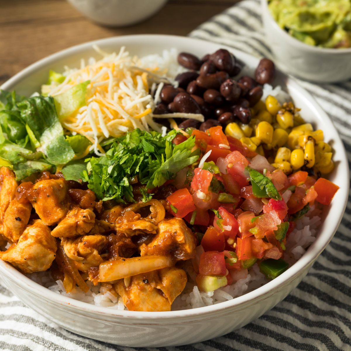 colorful chicken burrito bowl on a gray and white striped chicken towel.