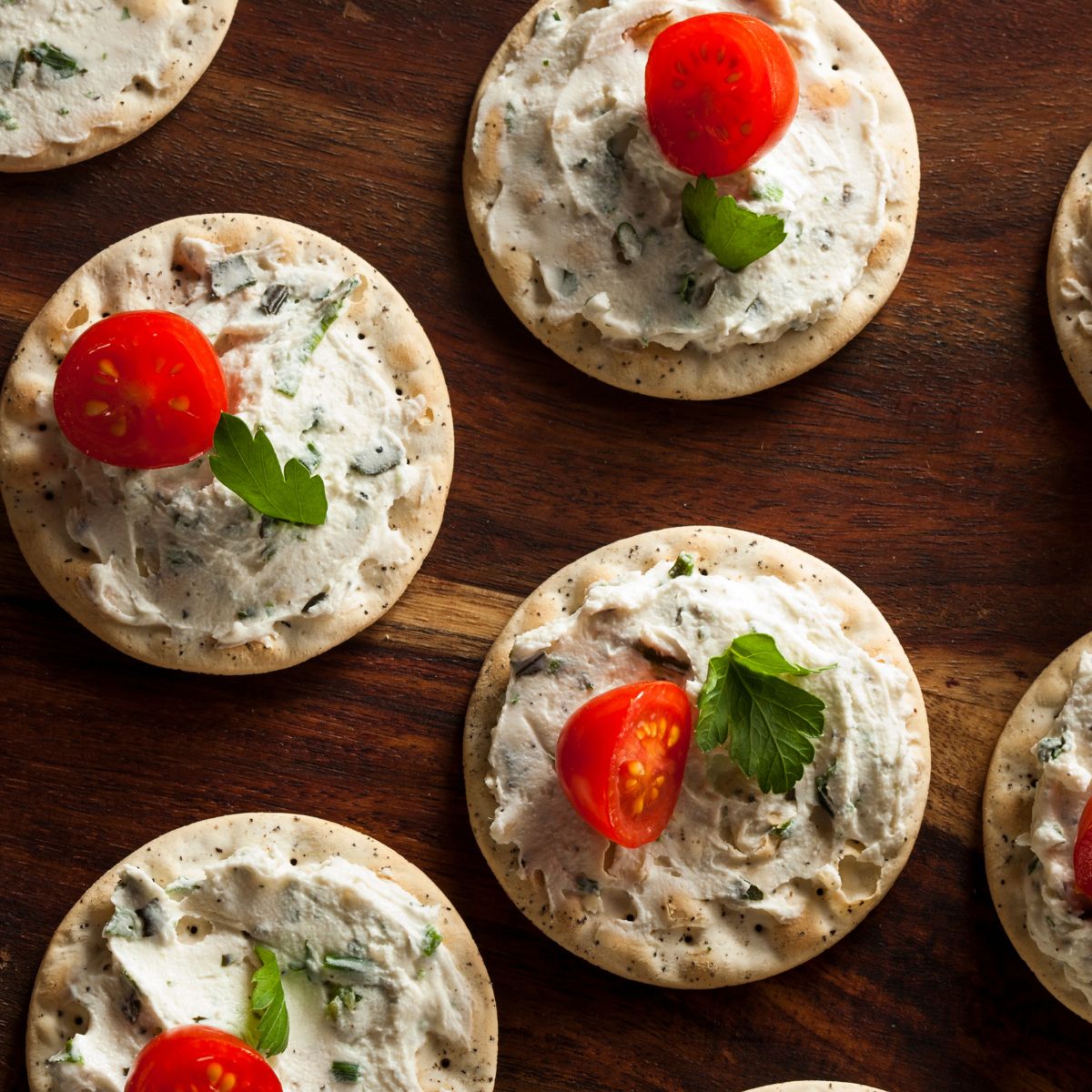 hors d’oeuvres: cheese spread on crackers with a topping of parsley and half of a cherry tomato. 