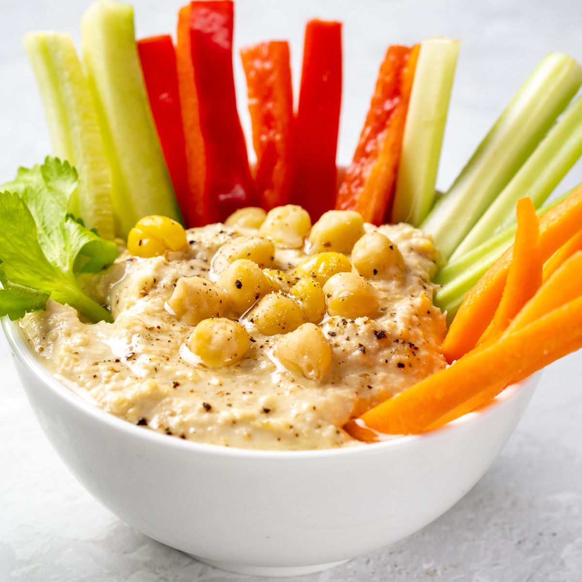 a bowl of hummus with fresh veggie sticks (carrots, celery, cucumber and red peppers).