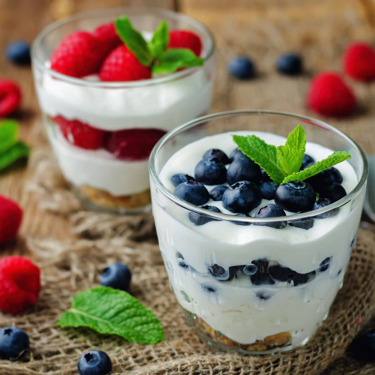 yogurt and berries in glass containers and decorated with mint sprigs.