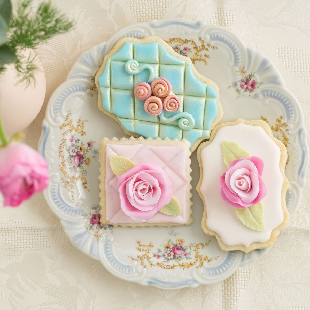 Beautifully decorated cookies in pastel colors on a pretty plate.