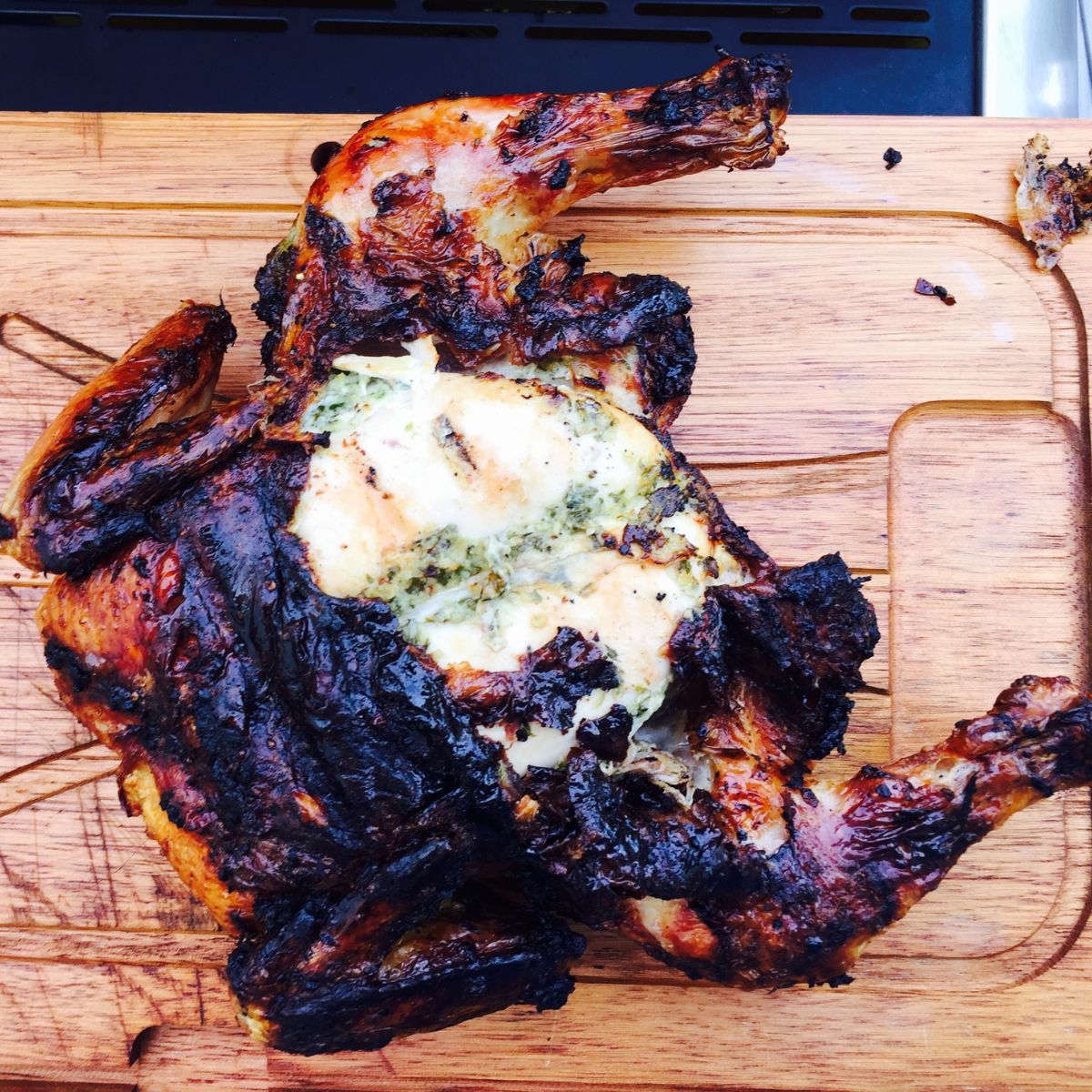 charred spatchcocked chicken on a wooden board