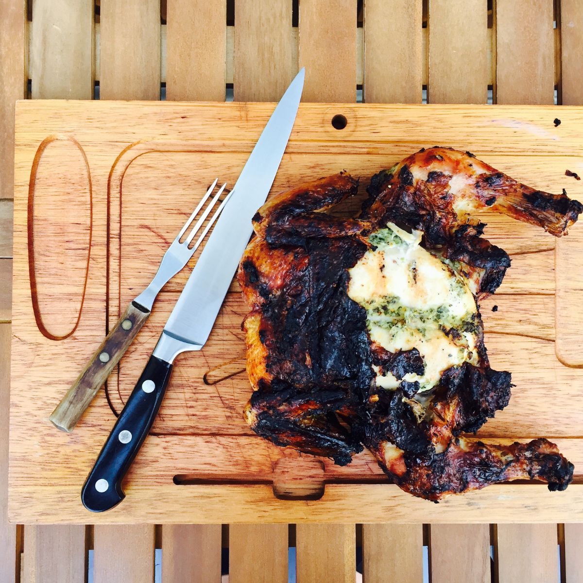 grilled spatchcocked chicken on a wooden cutting board.