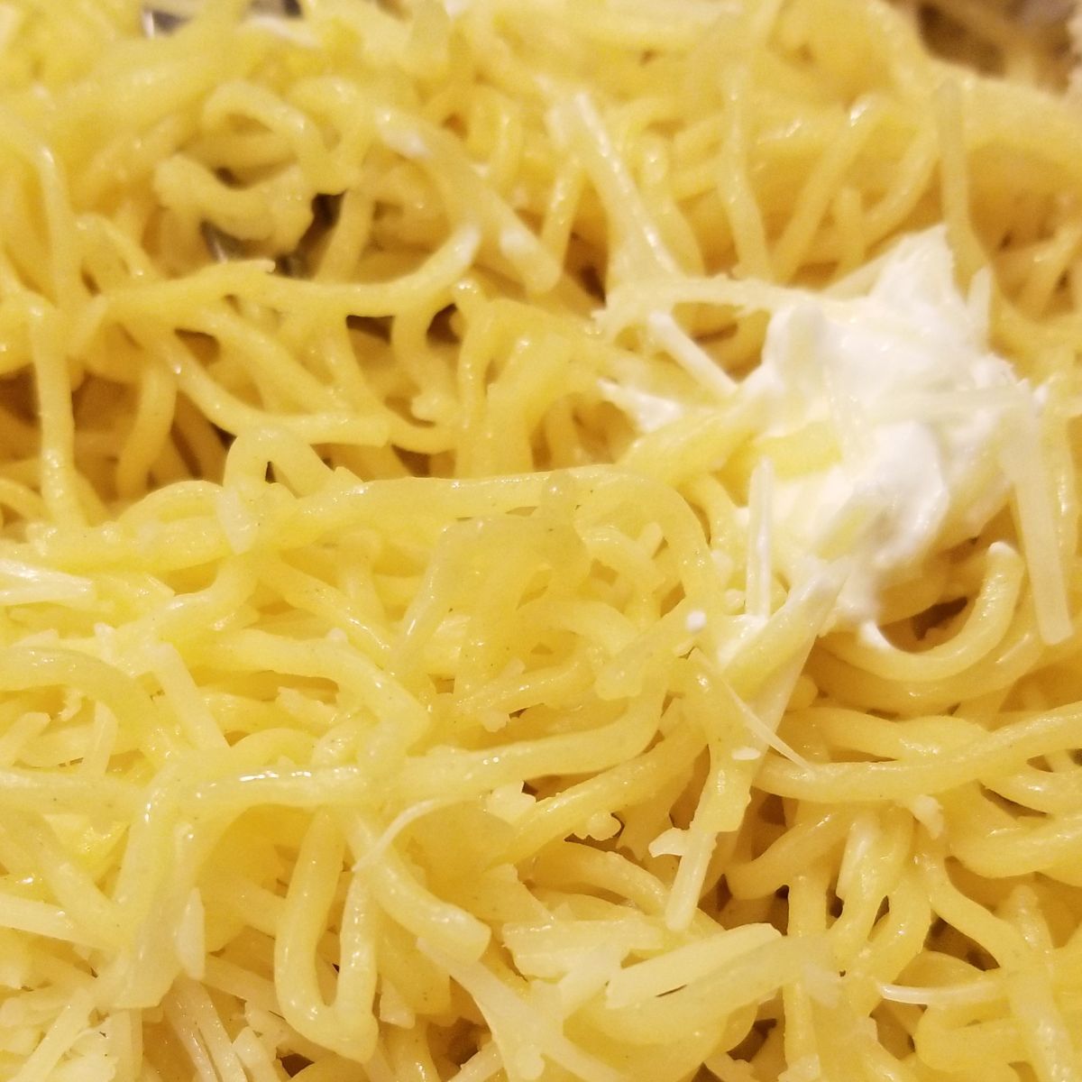 A dollop of butter on top of a bed of noodles. 