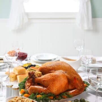 Thanksgiving dinner feast on a table: turkey, stuffing, carrots, green beans, cranberry sauce and more.