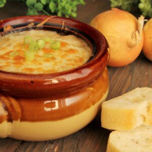 Cheesy onion soup in a ceramic two-tone earthy colored bowl.