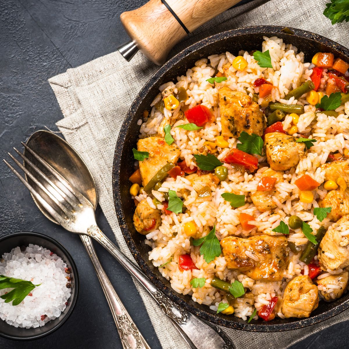 A pan of colorful fried rice with chicken chunks.