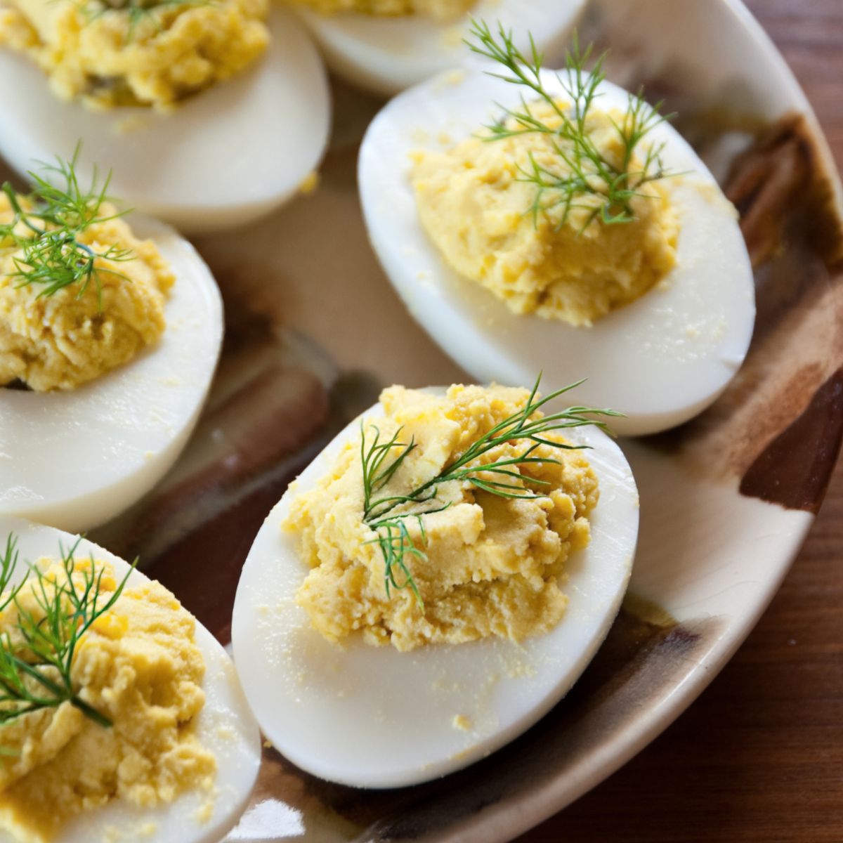 Deviled eggs on a plate with dill on top.