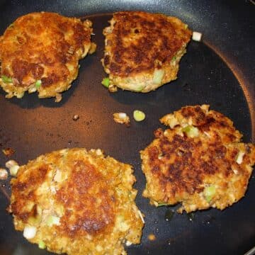 Salmon patties in a frying pan.