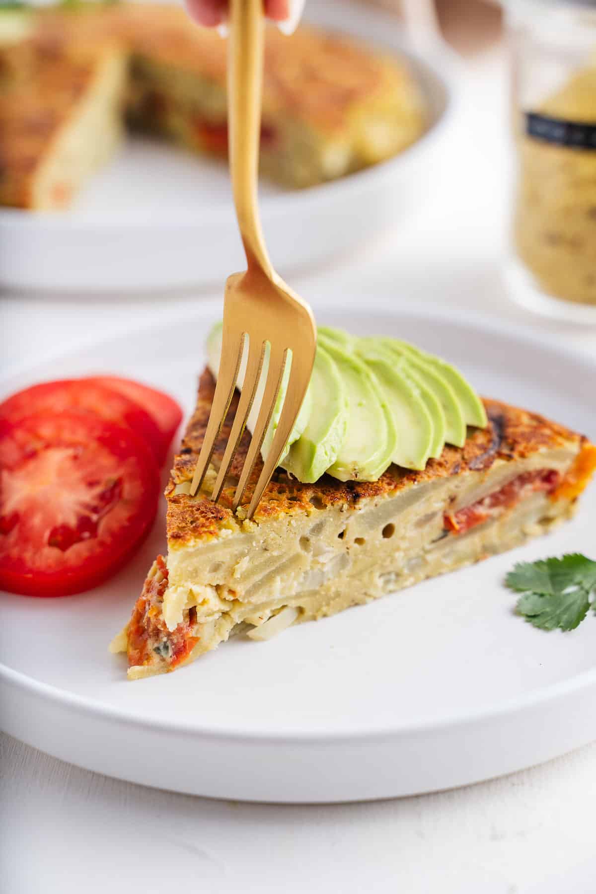 Spanish omelet with avocado sliced and sliced tomatoes. 