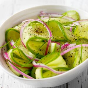A bowl of red onion and cucumber salad.