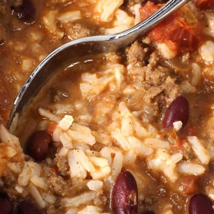 Close-up of a spoonful of Coconut Chili with ground beef, kidney beans, rice, and diced tomatoes in a thick, hearty sauce.