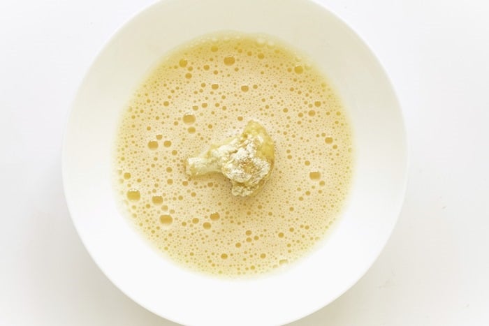 dipping cauliflower in flour and egg before deep frying