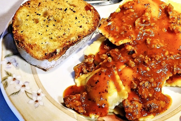 quick cheese ravioli meal using frozen ravioli and homemade marinara sauce and a side of garlic bread.