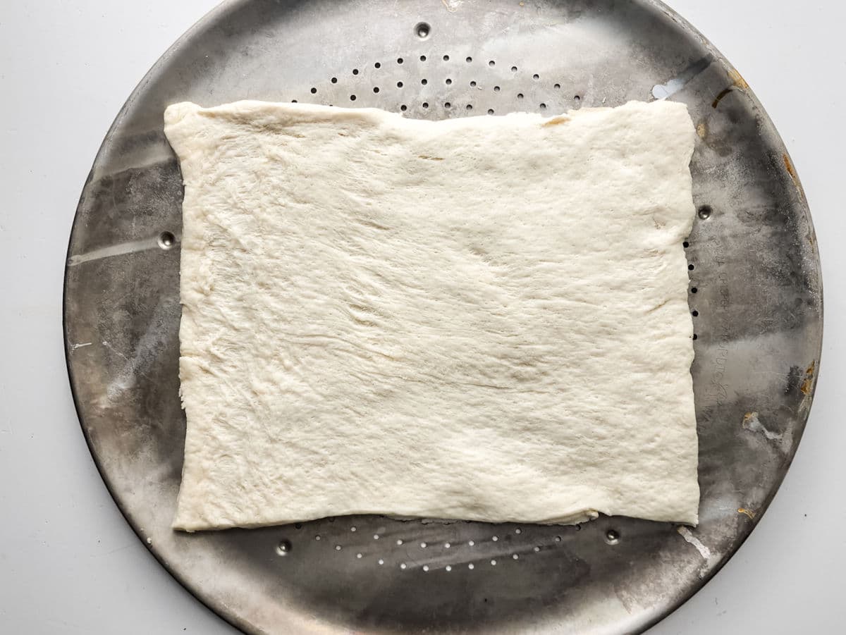unrolled pizza dough on pan