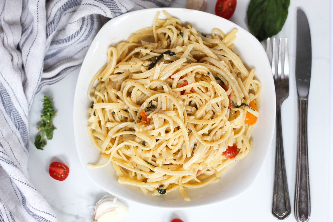 linguine on white plate with fork and knife