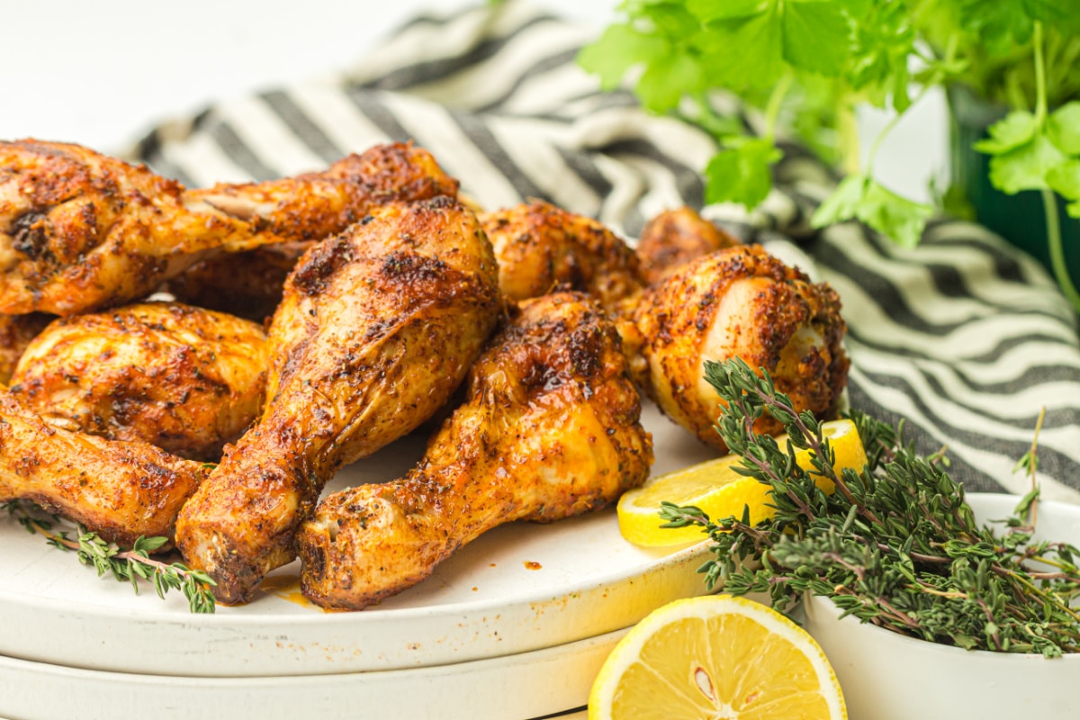 front view of air fryer chicken drumsticks on counter with lemon