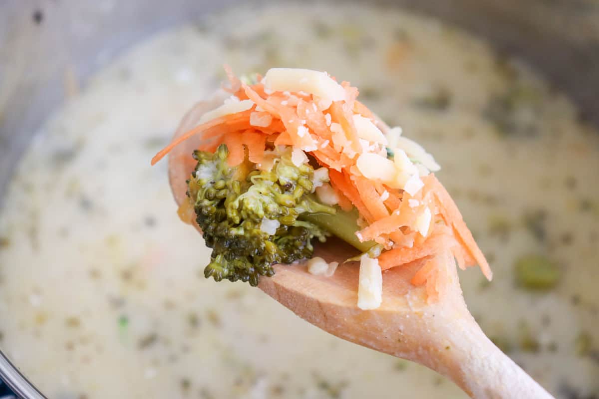 Broccoli Cheddar Cheese Soup on wooden spoon with extra cheese