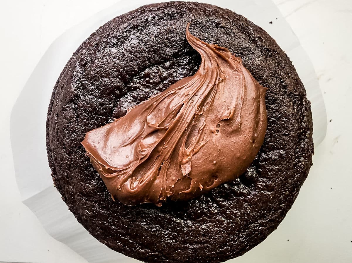 adding frosting to chocolate cake