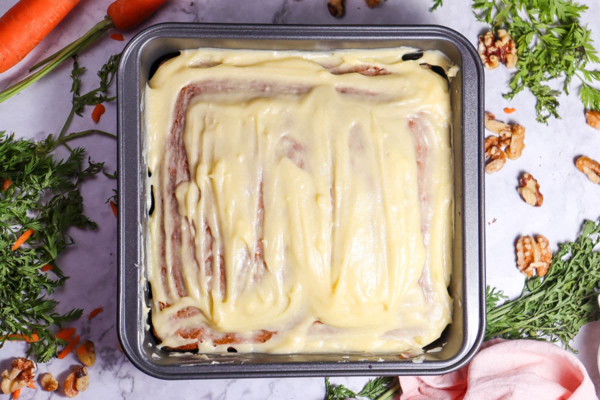 spreading frosting on cooled carrot cake