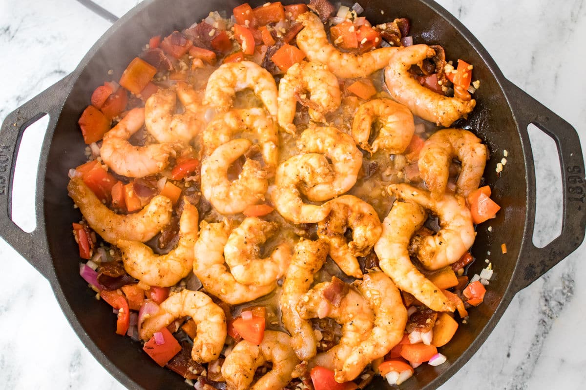 cooking shrimp in cast iron pan with bacon onions and peppers