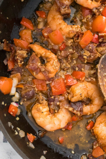 Cajun Shrimp and Grits shown in cast iron pan with spoon