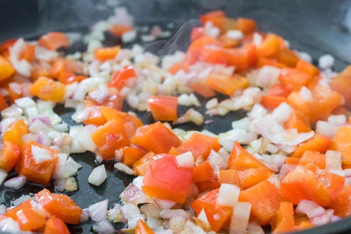 cooking olive oil in pan along with red bell pepper and onion.