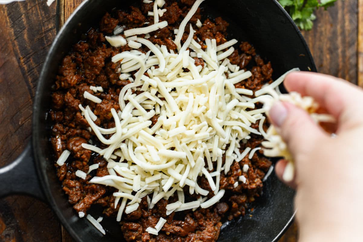 adding cheese to cast iron pan