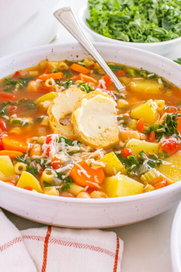 winter minestrone soup in white bowl with crusty bread