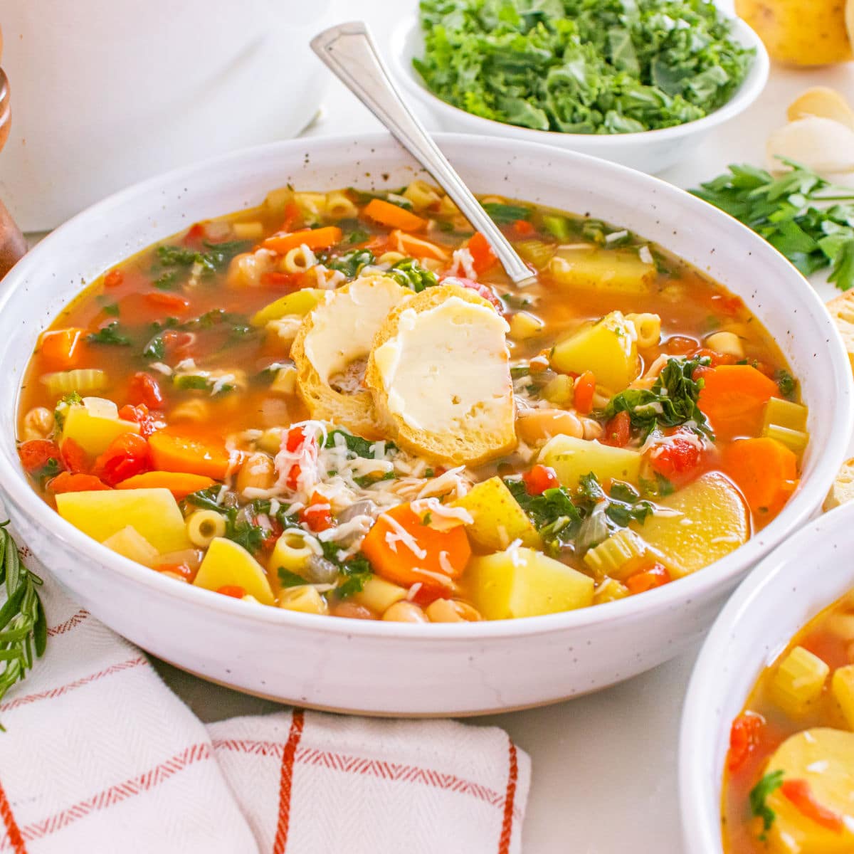 winter minestrone soup in white bowl with crusty bread